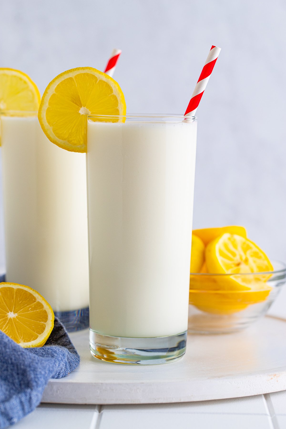 Two glasses of Frosted Lemonade with lemon garnish and straw.