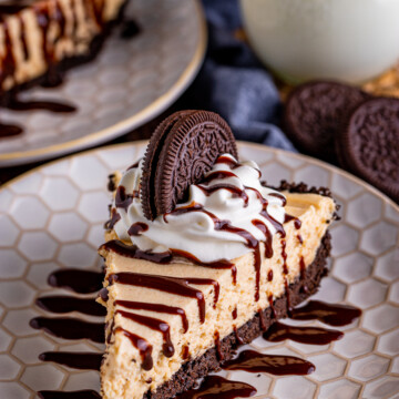 Slice of No Bake Peanut Butter Pie on plate drizzled with chocolate, topped with whipped cream and oreo.