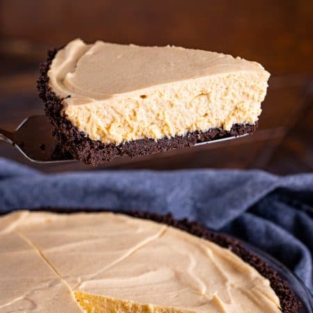 A no bake peanut butter pie with an Oreo crust, drizzled with chocolate and topped with whipped cream.