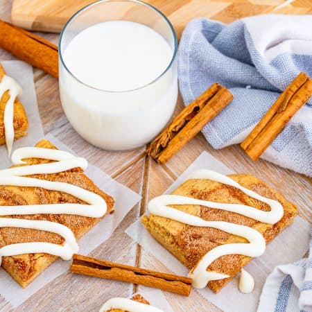 Overhead of glazed Cinnamon Roll Blondies with milk and cinnamon sticks.