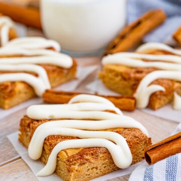 Cinnamon Roll Blondies on parchment paper in front of glass of milk.