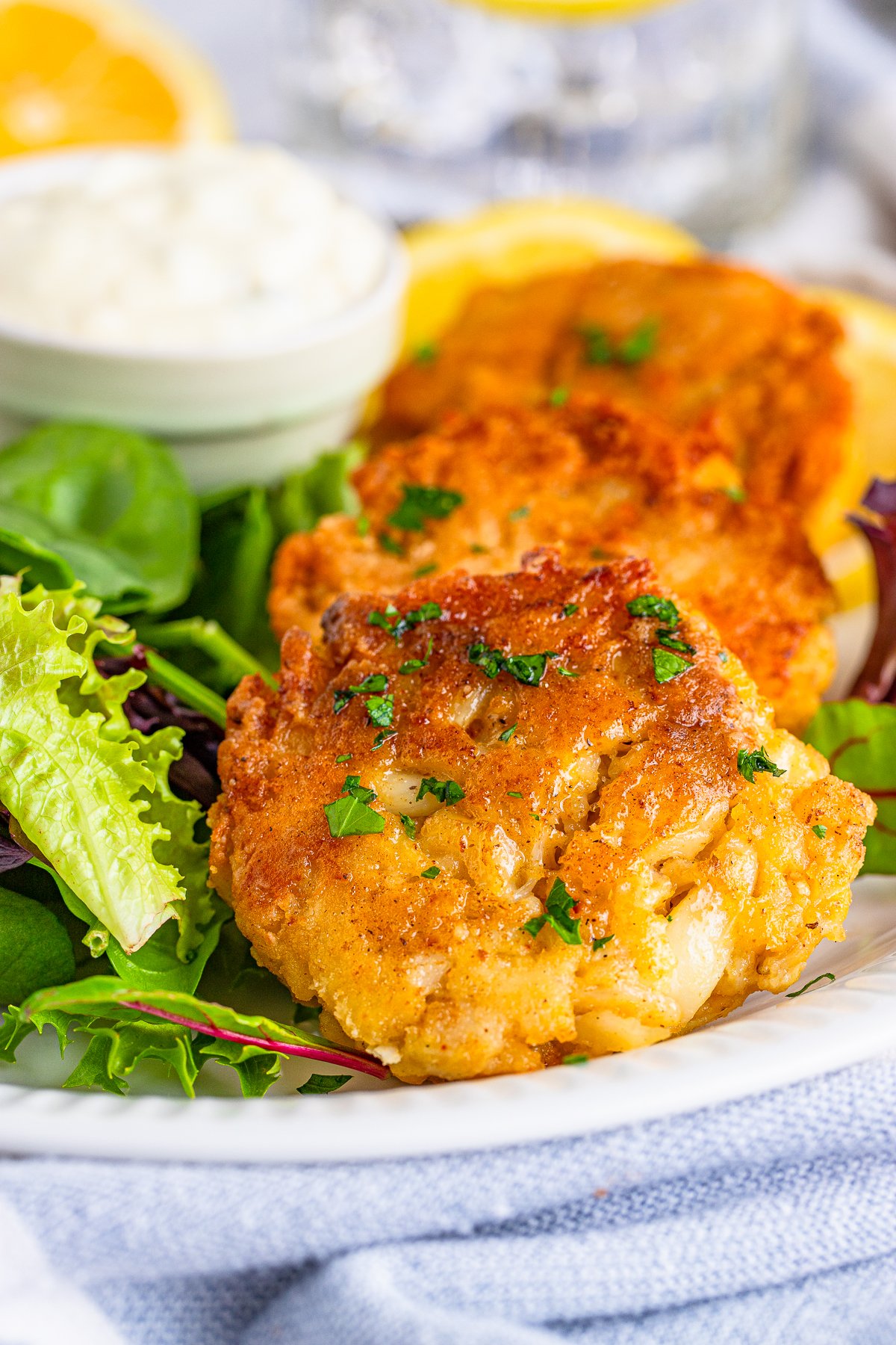 Close up of layered Crab Cake Recipe on plate with salad and dipping sauce.