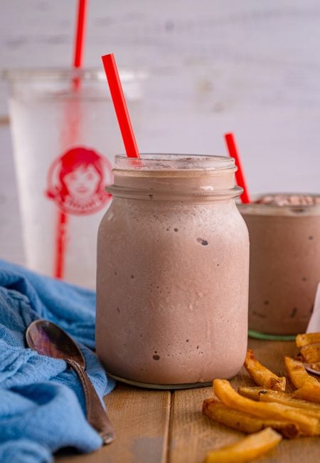 Wendy's Frosty Recipe in mason jar with fries and a water cup in background.