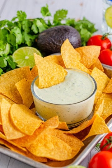 Avocado Ranch in bowl on tray with chips with chip in dip.
