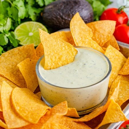 Avocado Ranch in bowl on tray with chips with chip in dip.