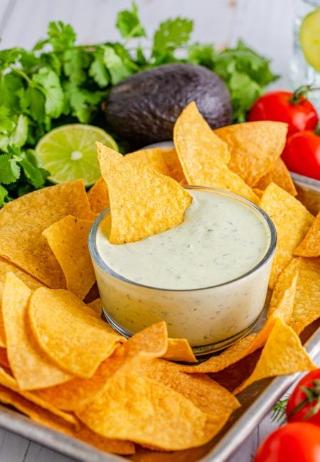 Avocado Ranch in bowl on tray with chips with chip in dip.