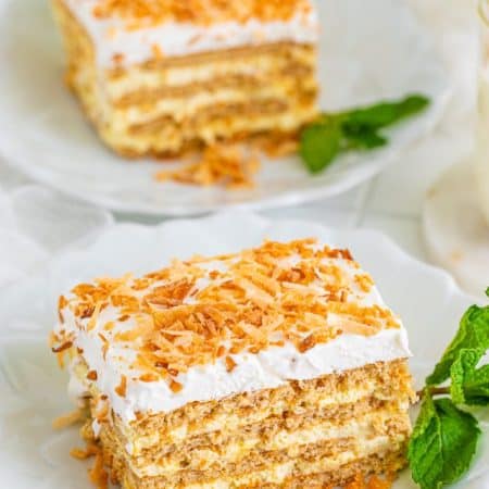 Two slices of Coconut Icebox Cake on plates with mint leaves.