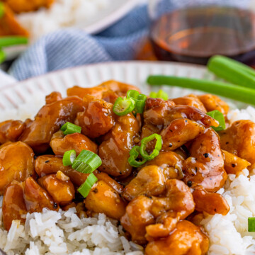 Close up of Bourbon Chicken over rice on white plate.