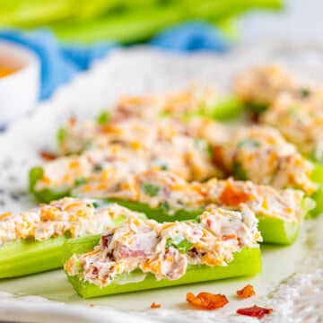 Cheddar Bacon Ranch Stuffed Celery Sticks lined up on white platter.