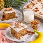Two slices of Hummingbird Cake on white plate with nuts on top and milk beside them.