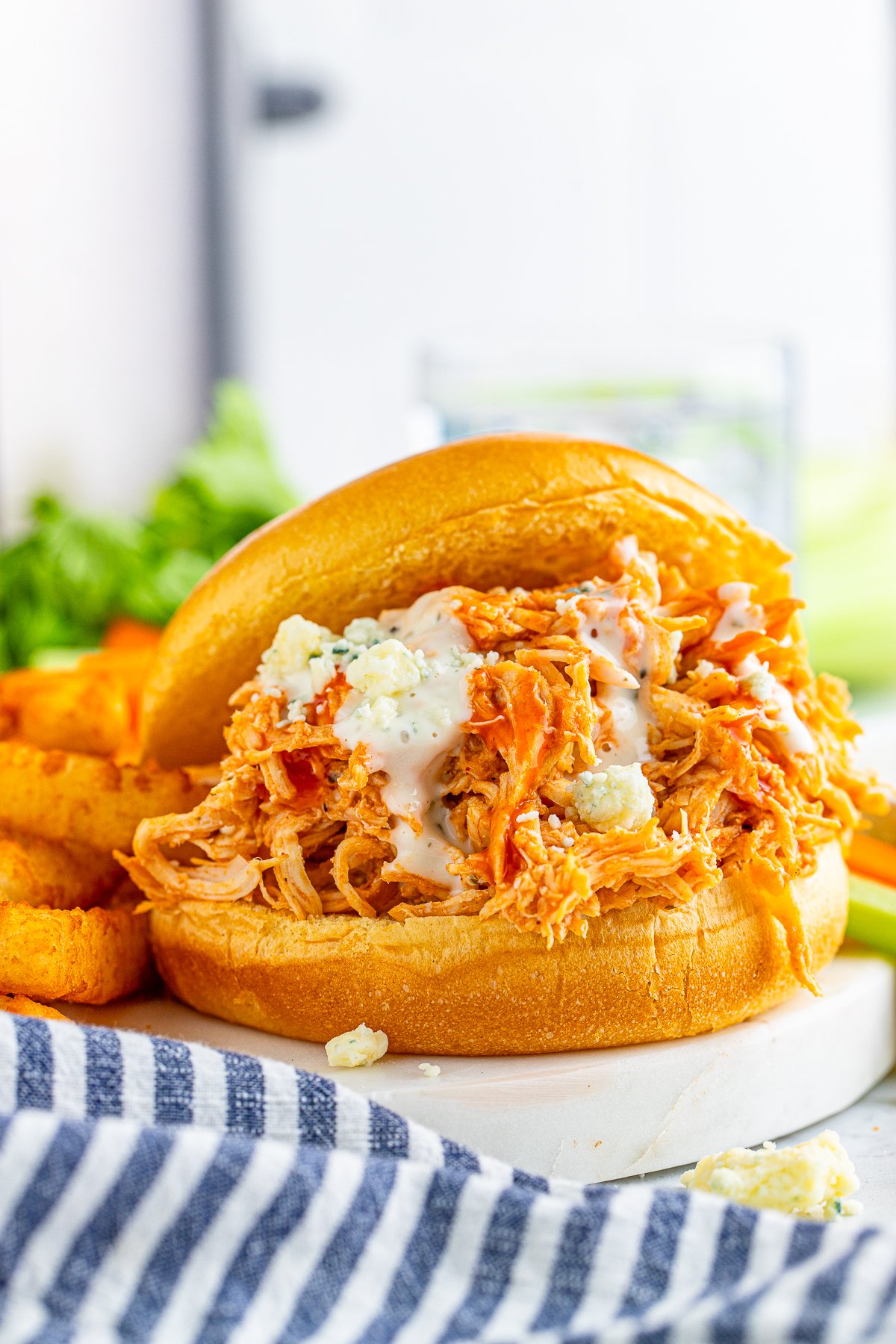 Close up of one finished Slow Cooker Buffalo Chicken Sandwiches next to fries.