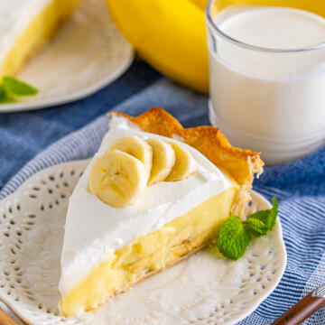 Close up of one slice of Banana Cream Pie on white plate topped with banana slices.