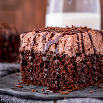 Close up side view of slice of Chocolate Poke Cake with chocolate syrup dripping down.