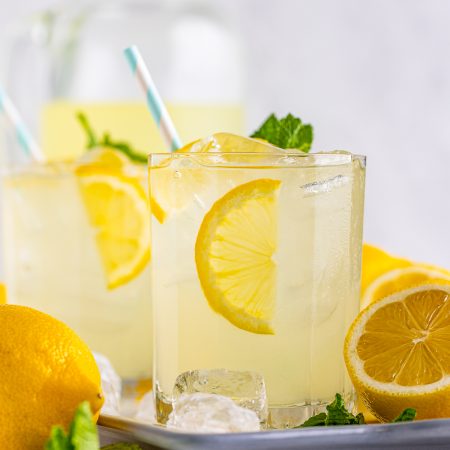 Straight on photo of Lemonade Recipe on tray with pitcher in background.