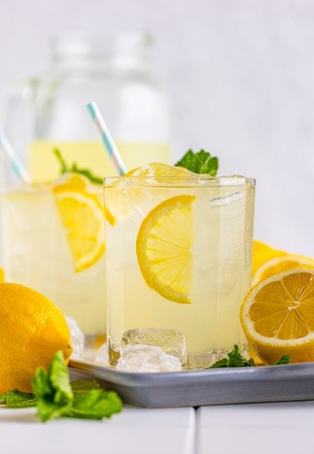 Straight on photo of Lemonade Recipe on tray with pitcher in background.