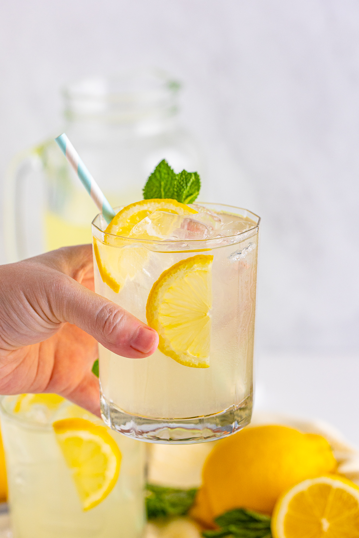 Hand holding up one glass of Lemonade.
