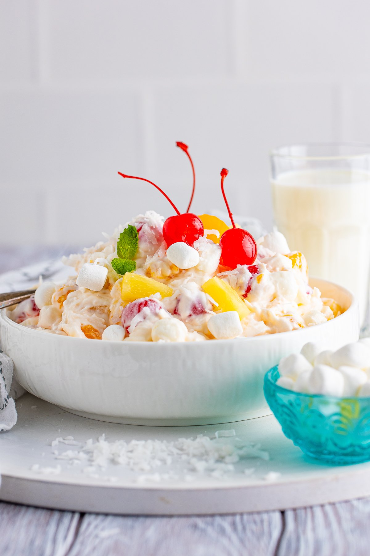 Serving dish of the Ambrosia Salad Recipe with milk behind bowl.