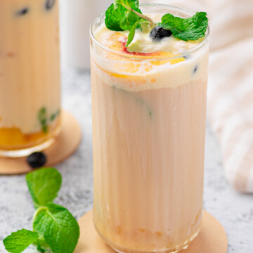 Close up of Creamy Peach Tea in tall glass with garnishes.