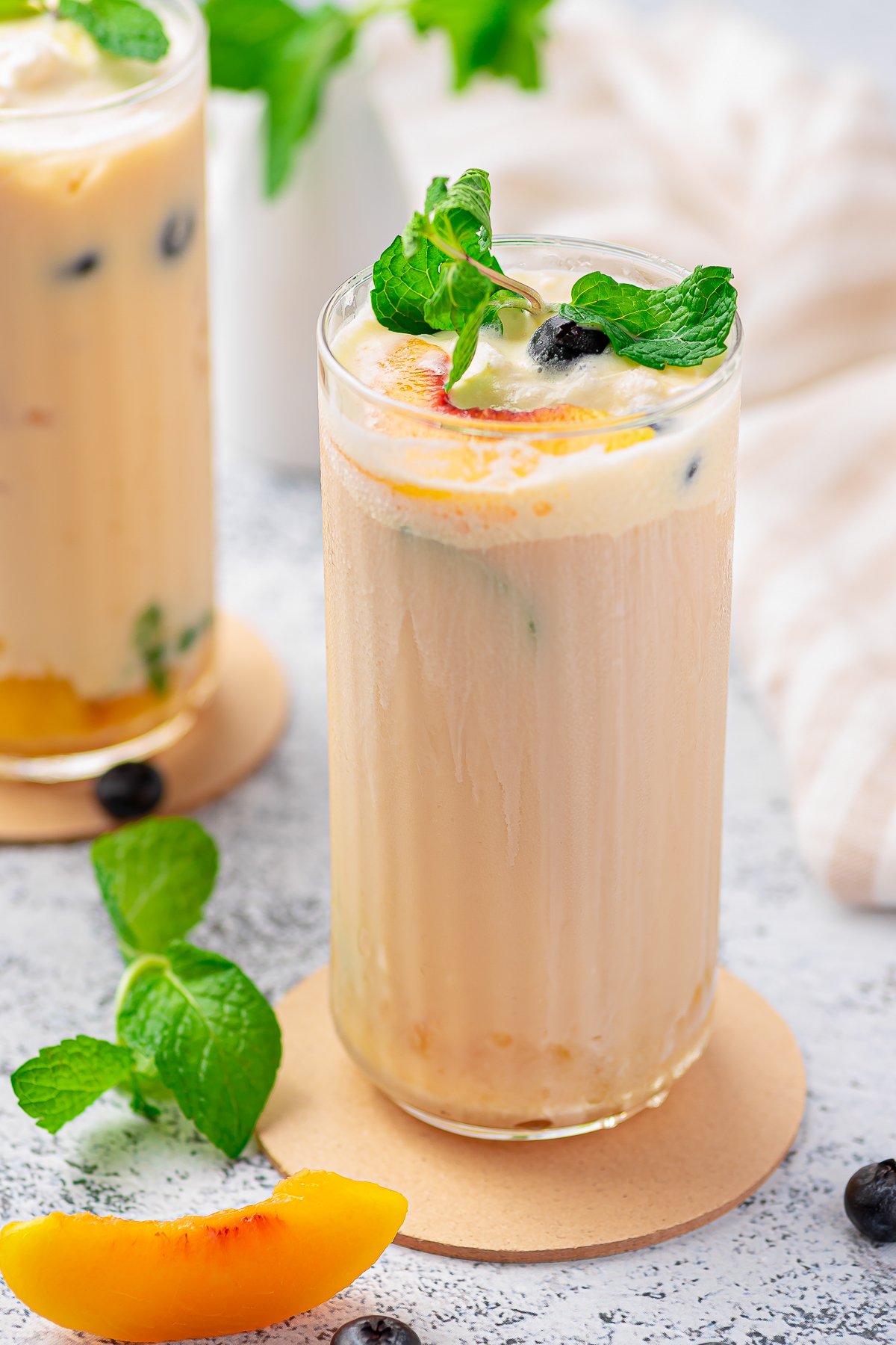 Close up of Creamy Peach Tea in tall glass with garnishes.
