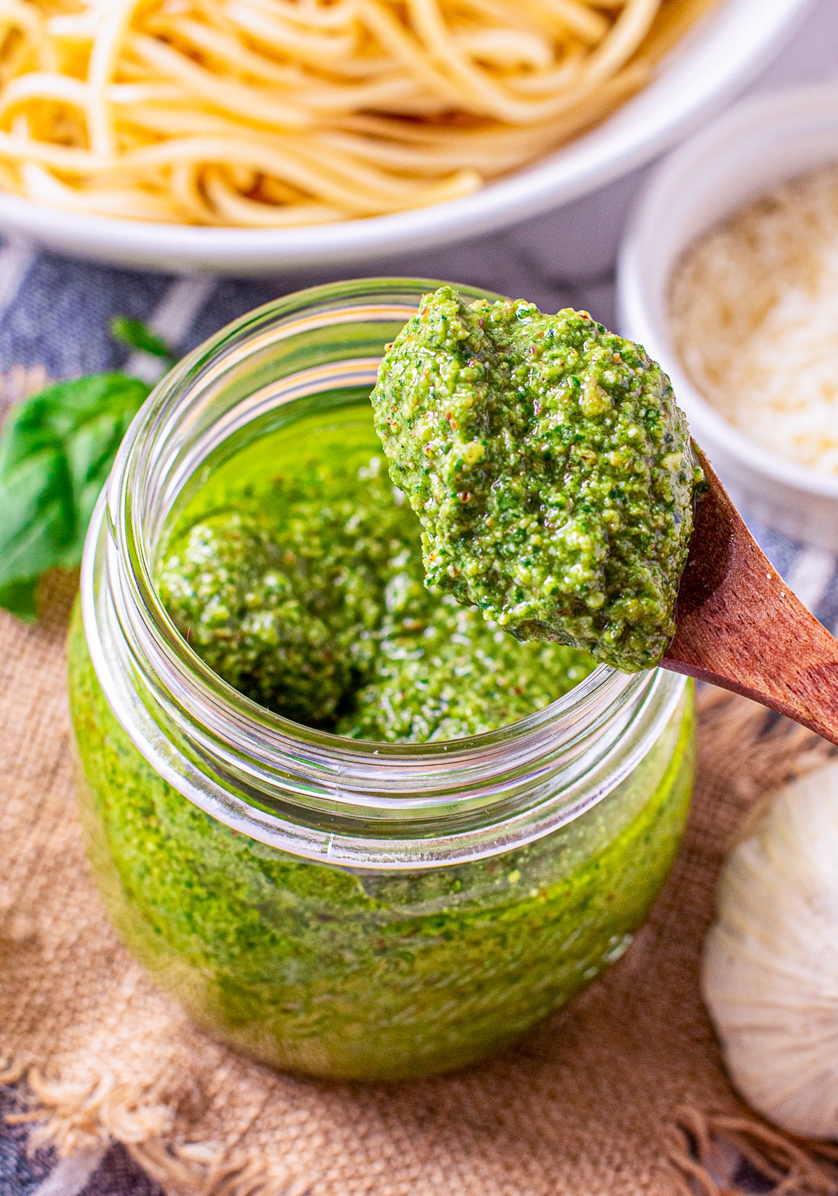Spoon holding up some pesto from jar.