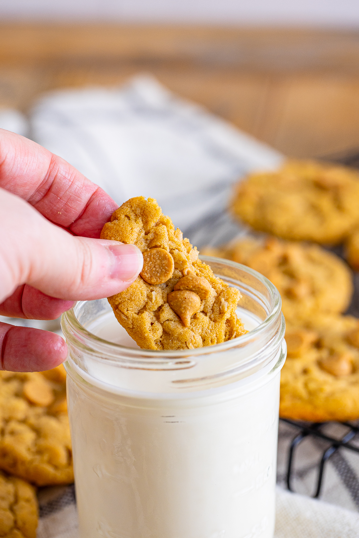 Hand dipping a portion of the Peanut Butter Oatmeal Cookie in milk.