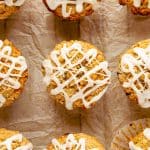 Glazed chocolate chip oatmeal muffins with streusel topping on parchment paper.
