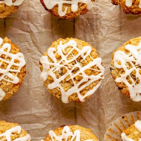 Glazed chocolate chip oatmeal muffins with streusel topping on parchment paper.