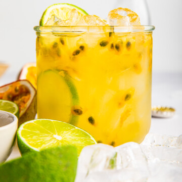 Close up of Passion Fruit Gin Fizz with limes around glass.