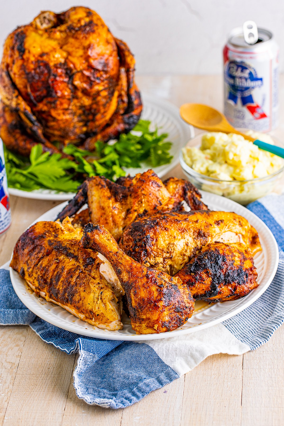 Beer Can Chicken on plate with whole chicken and beer in background.