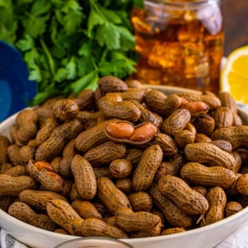 Boiled Peanuts in large bowl with seasoning and tea in background and some peanuts being showed open.