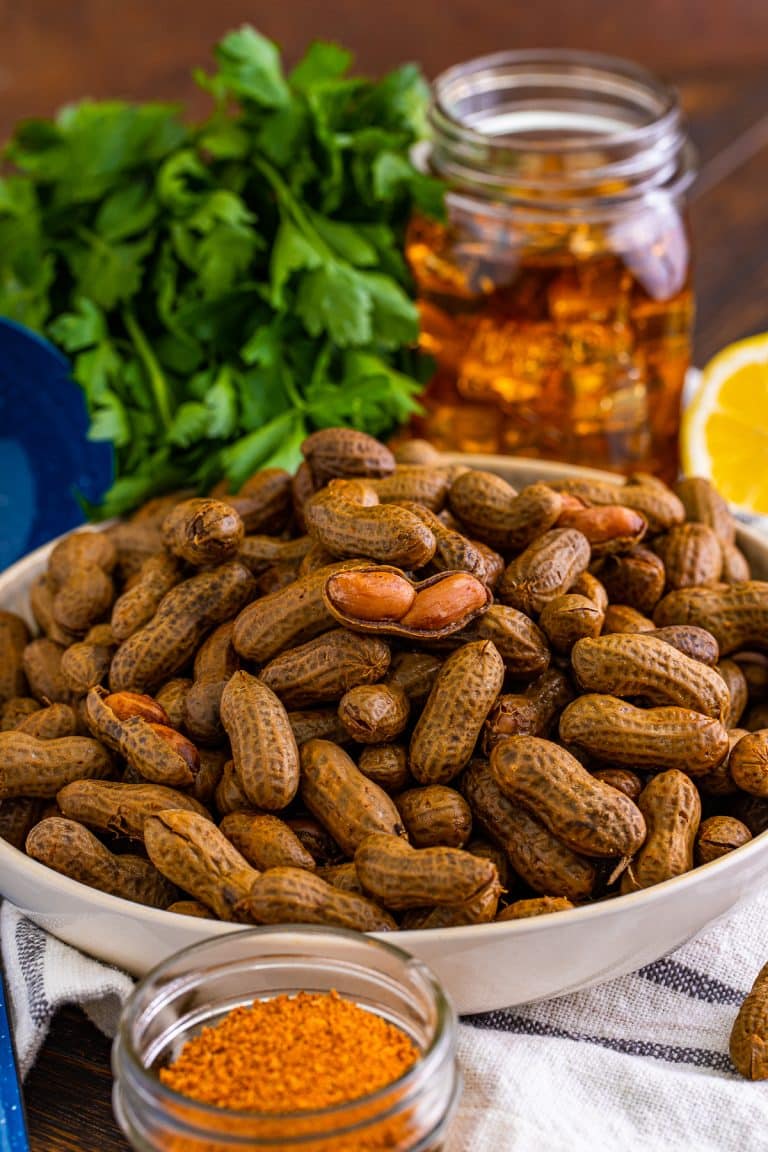 Boiled Peanuts in large bowl with seasoning and tea in background and some peanuts being showed open.