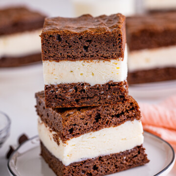 Two stacked Brownie Ice Cream Sandwiches on white plate.