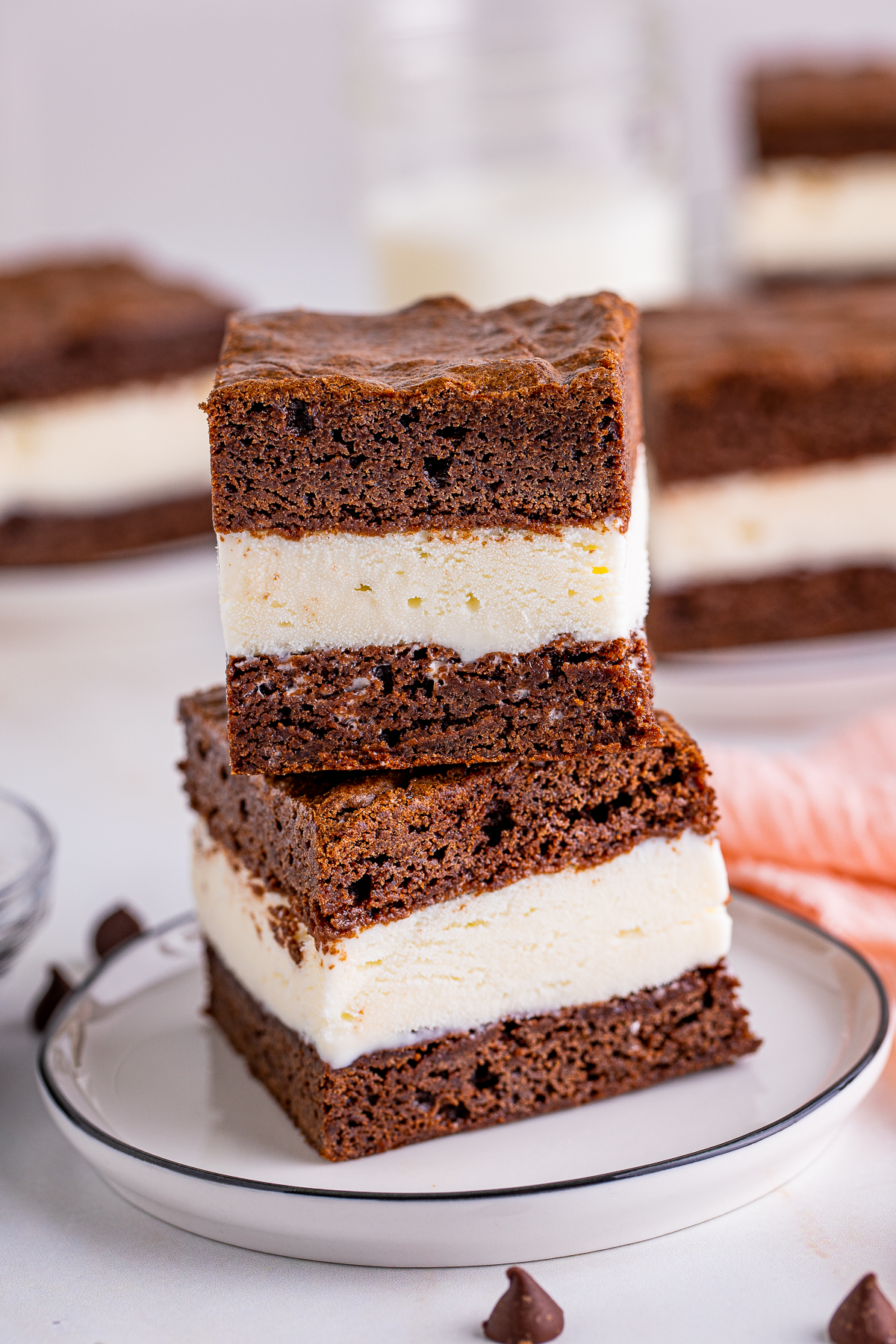 Two stacked Brownie Ice Cream Sandwiches on white plate.