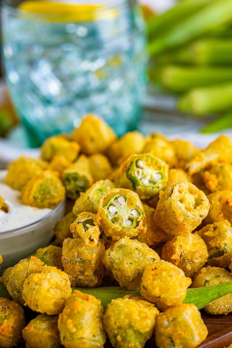 A heaping pile of golden crispy fried okra with a bowl of ranch dressing for dipping