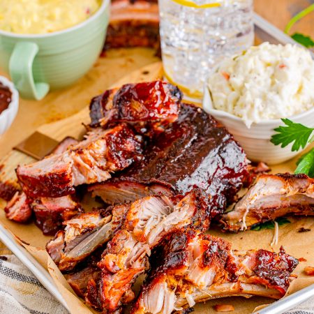 Smoked Ribs on tray with parchment with sides and drink behind it.