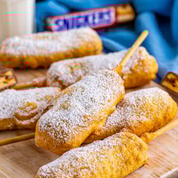Close up of stacked snickers bars covered with powdered sugar.