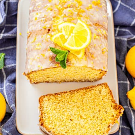 Finished bread loaf with slice laying on white platter.