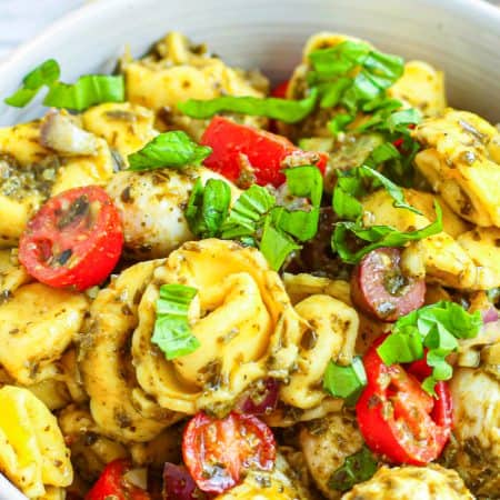 Close up of Tortellini Pasta Salad in bowl showing mixed ingredients.