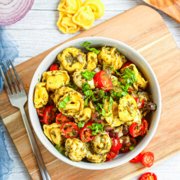 Overhead photo of Salad in bowl on cutting board with ingredients around it.