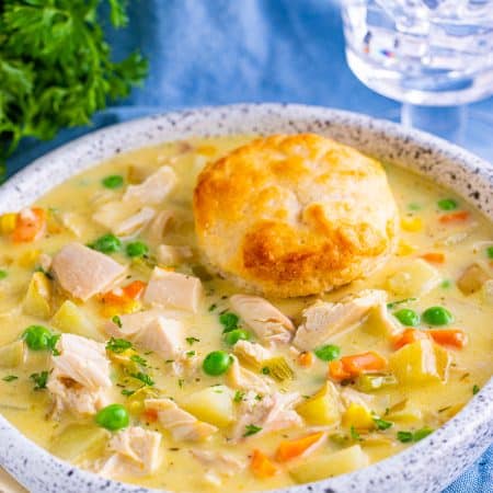 Close up of Chicken Pot Pie Soup in bowl topped with a biscuit.