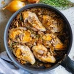 A skillet of chicken and mushrooms with caramelized onions and thyme.