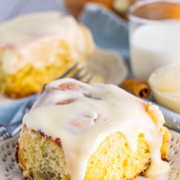 Close up of on of the Soft Cinnamon Rolls on plate with icing going down the sides.
