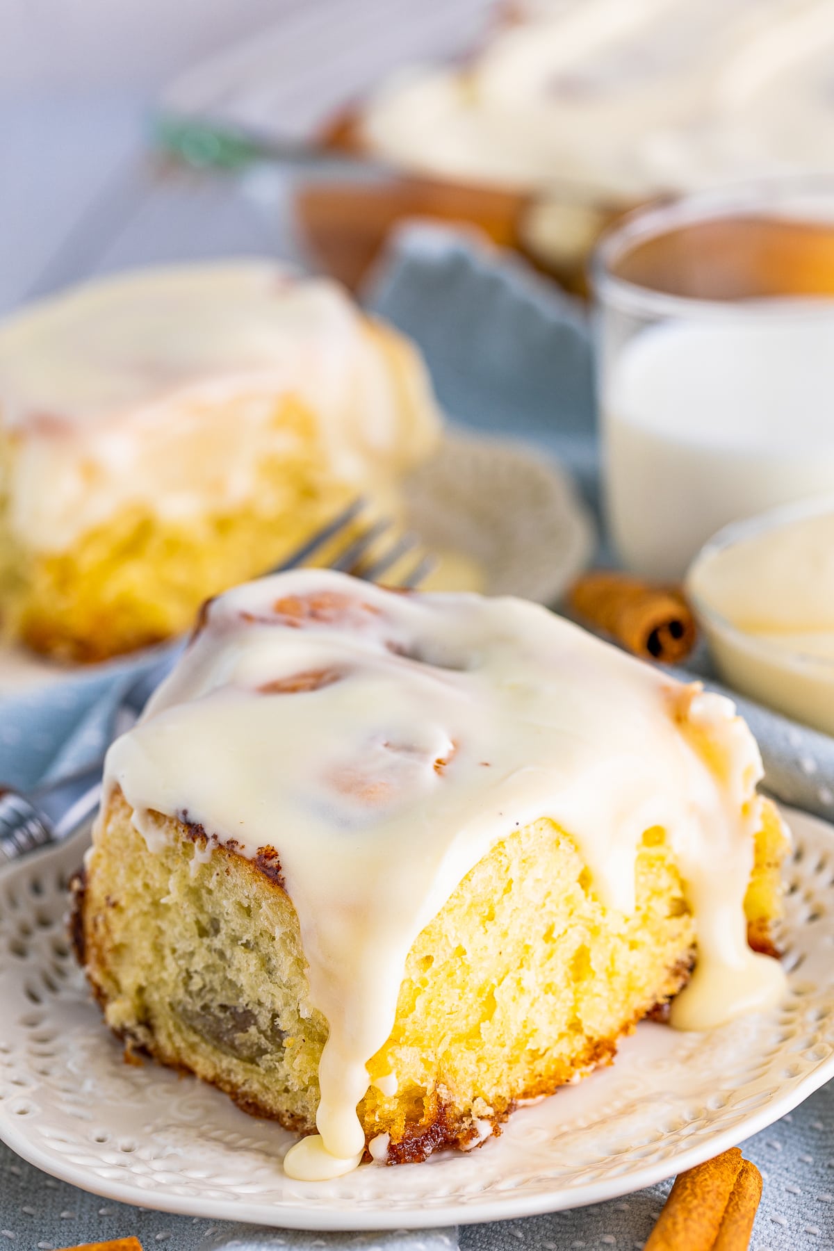 Close up of on of the Soft Cinnamon Rolls on plate with icing going down the sides.