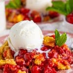 Close up of Cherry Dump Cake on vintage plate with ice cream and mint.