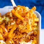 A cheesy scoop of baked ziti being lifted from the baking dish