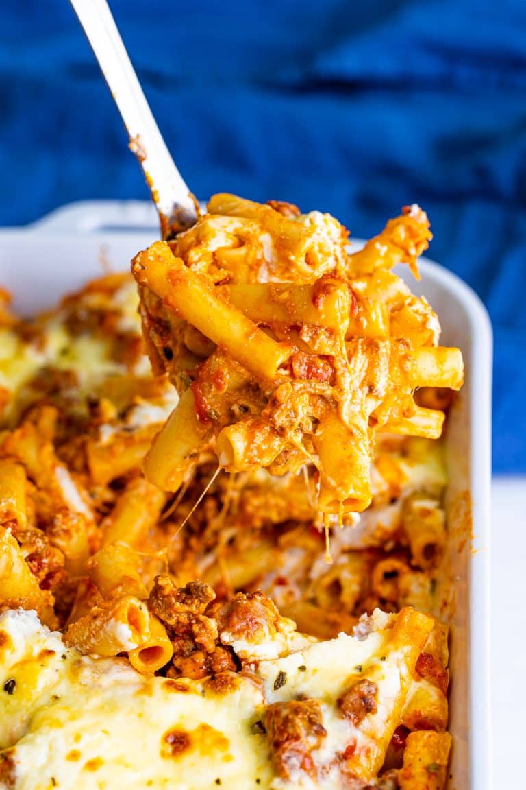 A cheesy scoop of baked ziti being lifted from the baking dish
