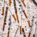 A spread of Chocolate Covered Pretzel Rods decorated as mummies, spider webs, ghosts, and sprinkle styles.