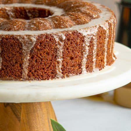 Bundt Cake on cake platter with glaze dripping down the side.