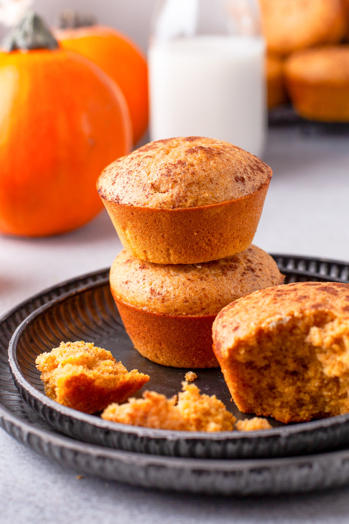 Two stacked Pumpkin Cornbread Muffins on plate with on up front with bite taken out.