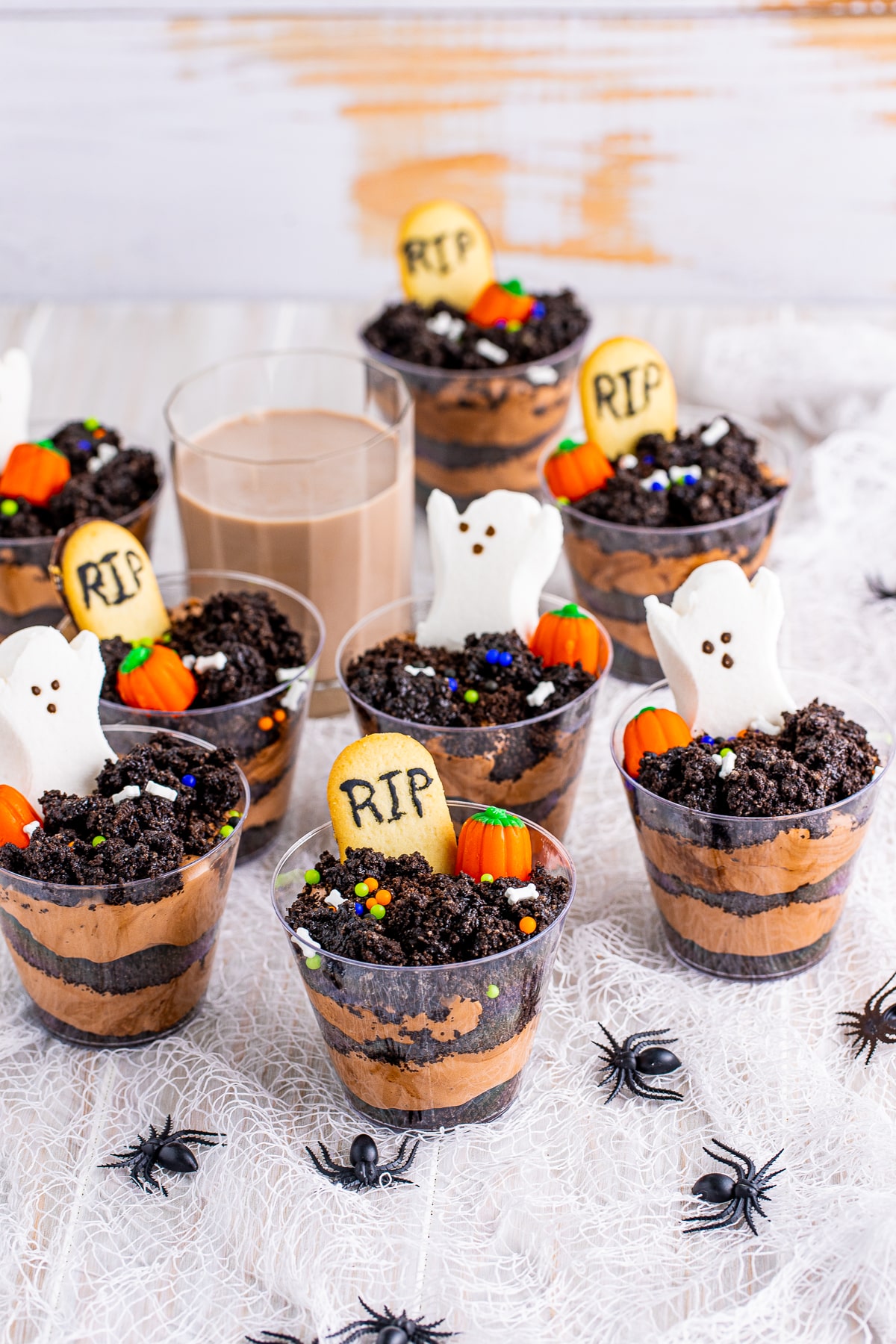 Dirt Cups spread out over a white linen with chocolate milk in background.